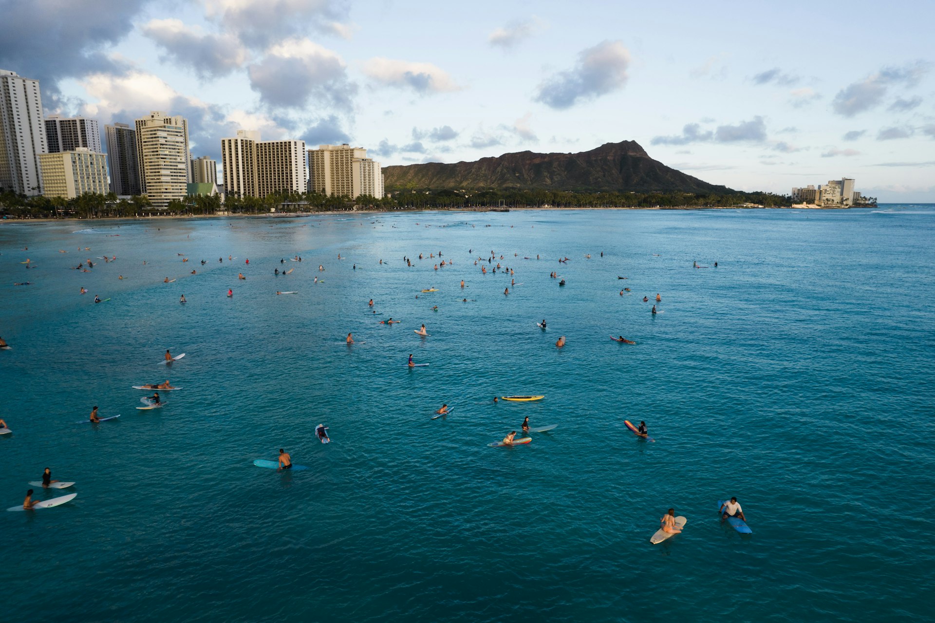 Waikīkī's shoreline and hotels seen from the water, with swimmers in the foreground and Diamond Head beyond