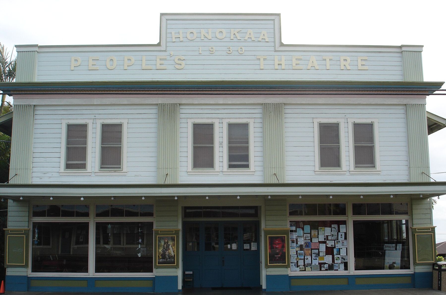 The pale green and white false-front facade of the Honokaa People’s Theatre, with ‘1930’ and the theater’s name at the top and poster cases beside the doors.