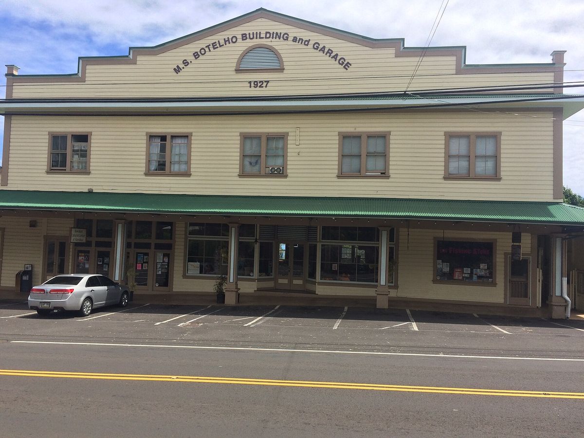 The cream-colored two-story M.S. Botelho Building and Garage, dated 1927, with a green awning over the sidewalk.