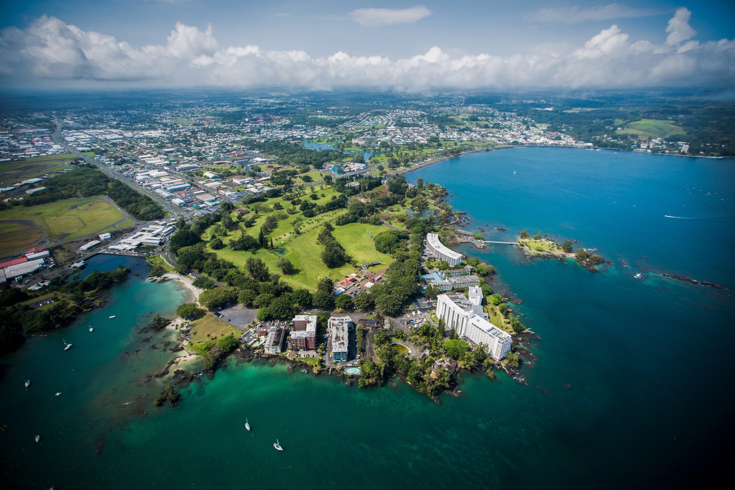 Aerial view of Hilo showing the Waiākea Peninsula, its hotels and gardens, and turquoise Hilo Bay with the town beyond