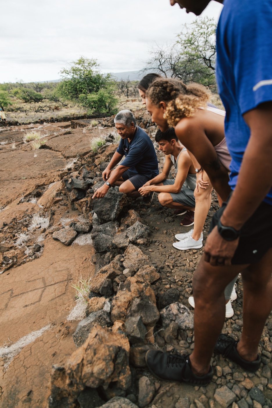 Visitors looking down at petroglyphs carved into lava rock at the Puakō petroglyph preserve