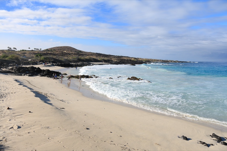 Kua Bay with white sand, turquoise water and dark lava rock in the foreground
