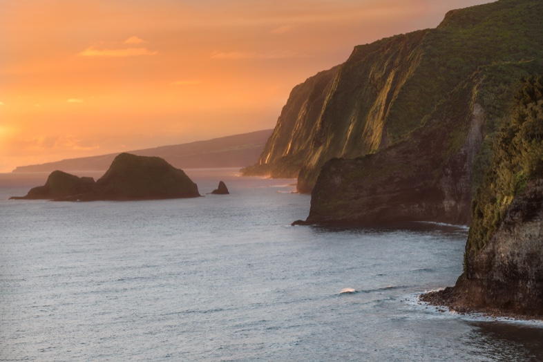 Steep green sea cliffs meeting the ocean at Pololū Valley Lookout