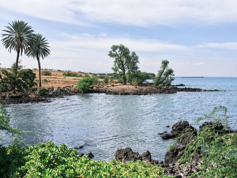 A coastal hiking trail over black lava rock toward the blue ocean on the Ala Kahakai National Historic Trail