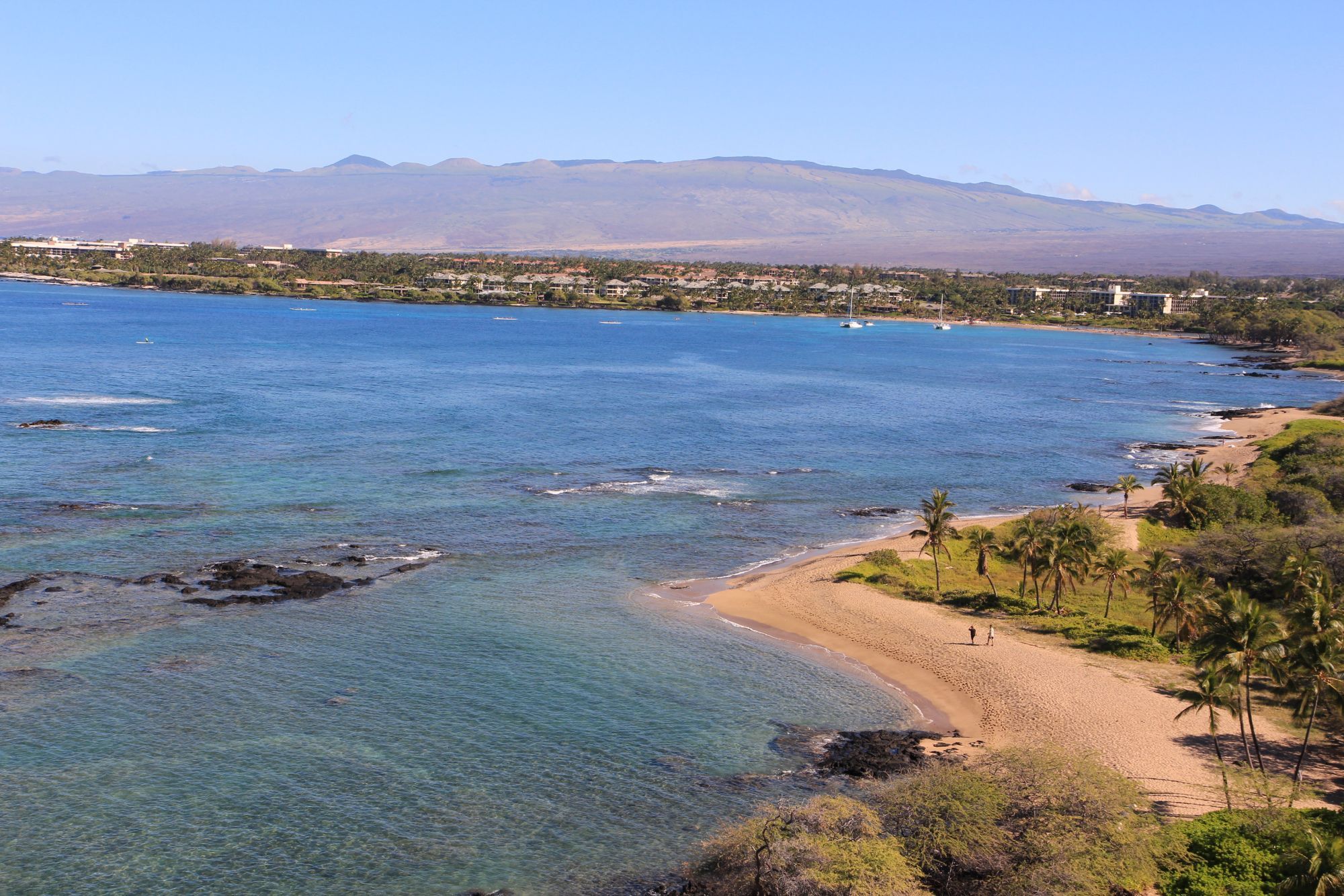 Kona Coast shoreline and bay with Hualālai and Mauna Kea behind