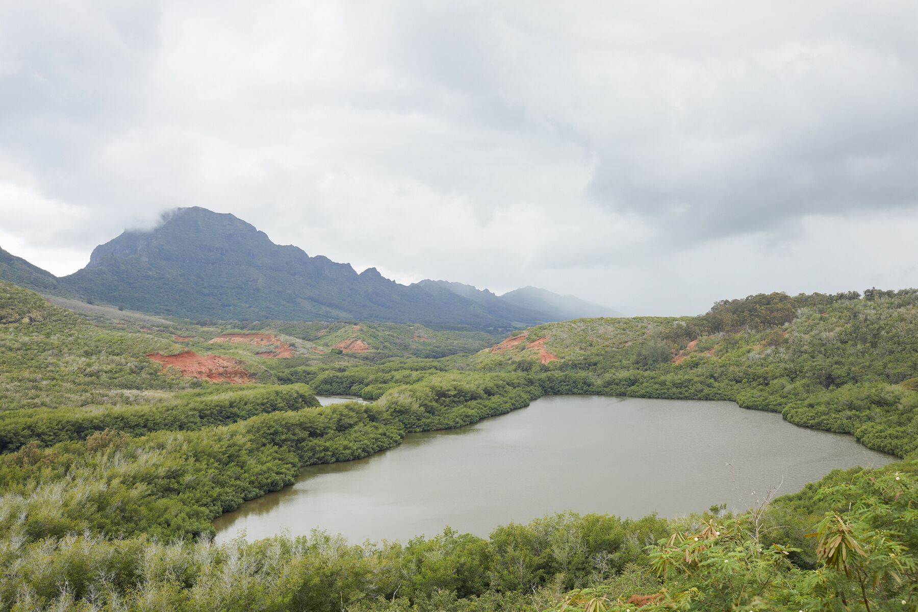 Alakoko (Menehune) Fishpond seen from above, with green hills under a cloudy sky