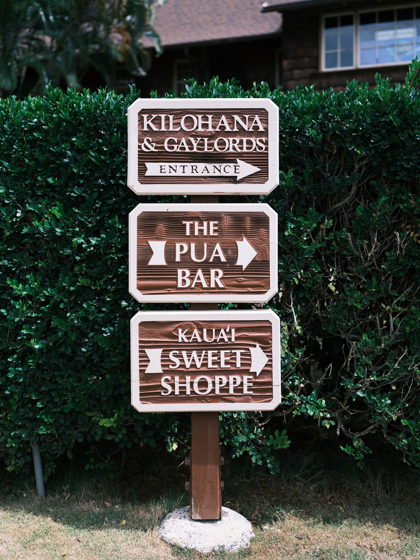 A wooden signpost at the Kilohana and Gaylord’s entrance, with arrows for The Pua Bar and Kauaʻi Sweet Shoppe