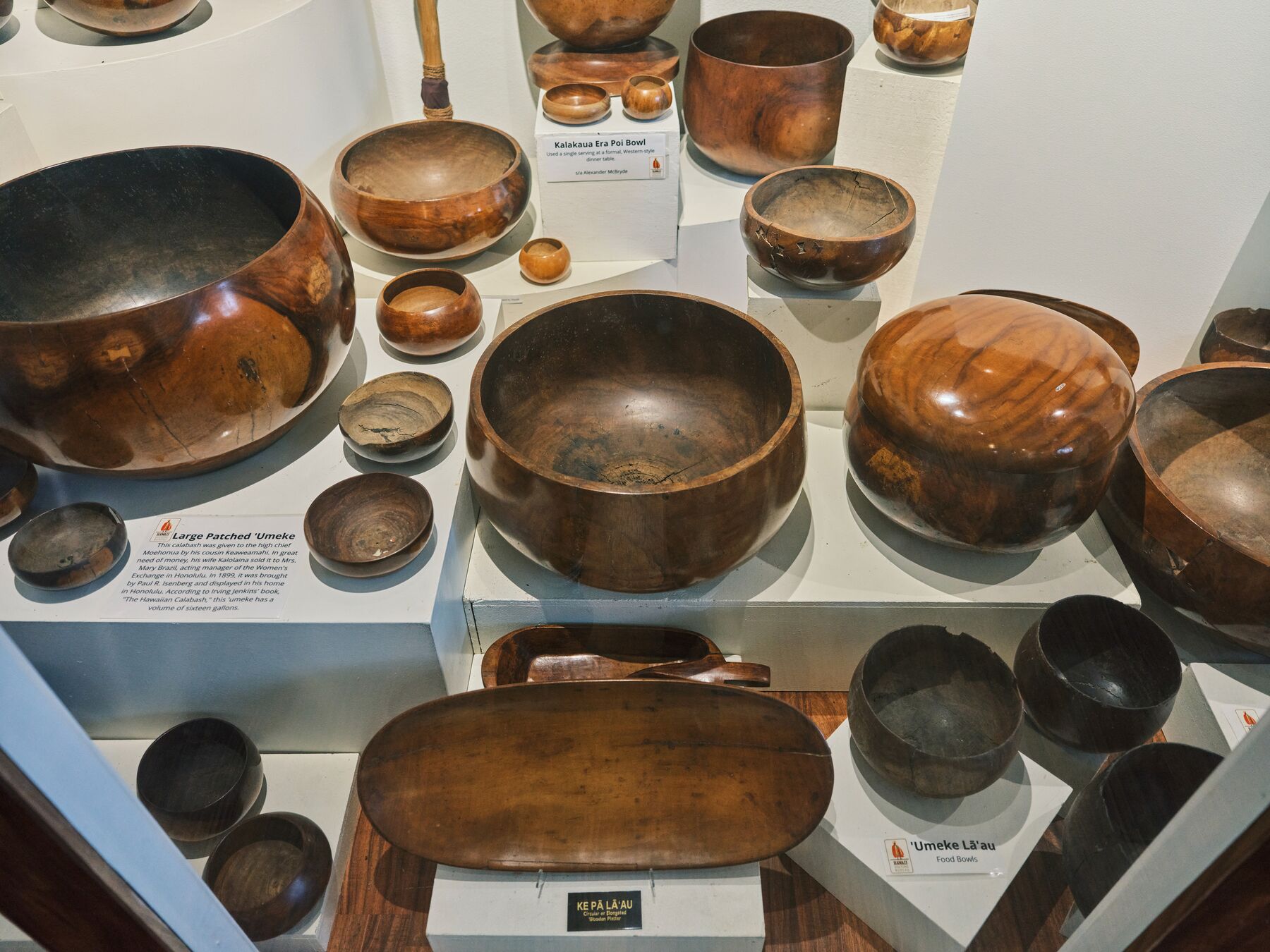A display of polished wooden ʻumeke bowls in a museum case