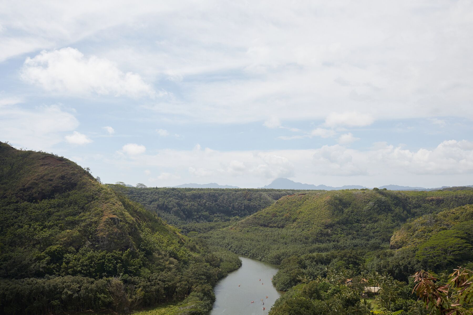 Looking down on the Wailua River winding through a deep green valley under soft cloud