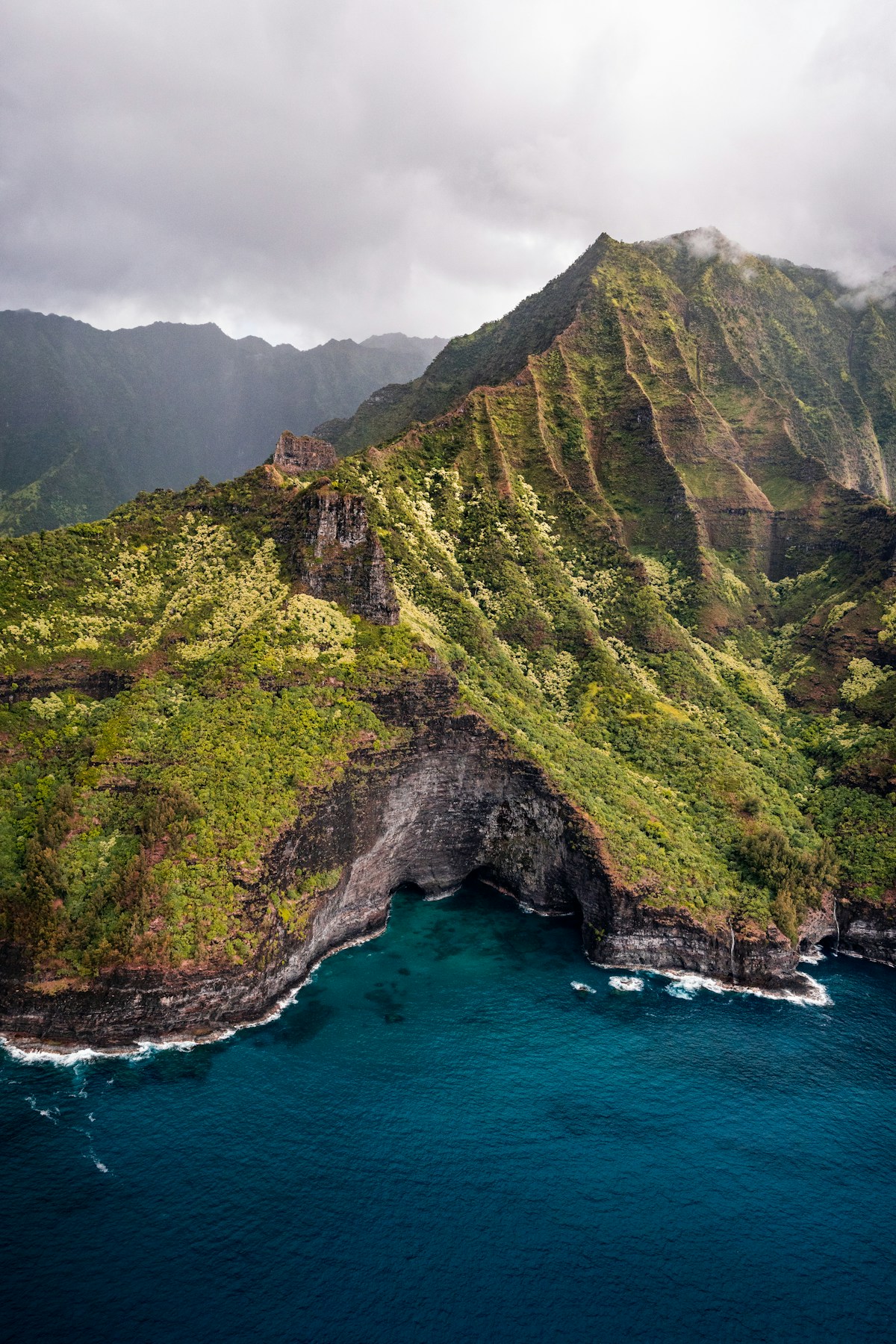Green Nāpali Coast cliffs rising above deep blue ocean