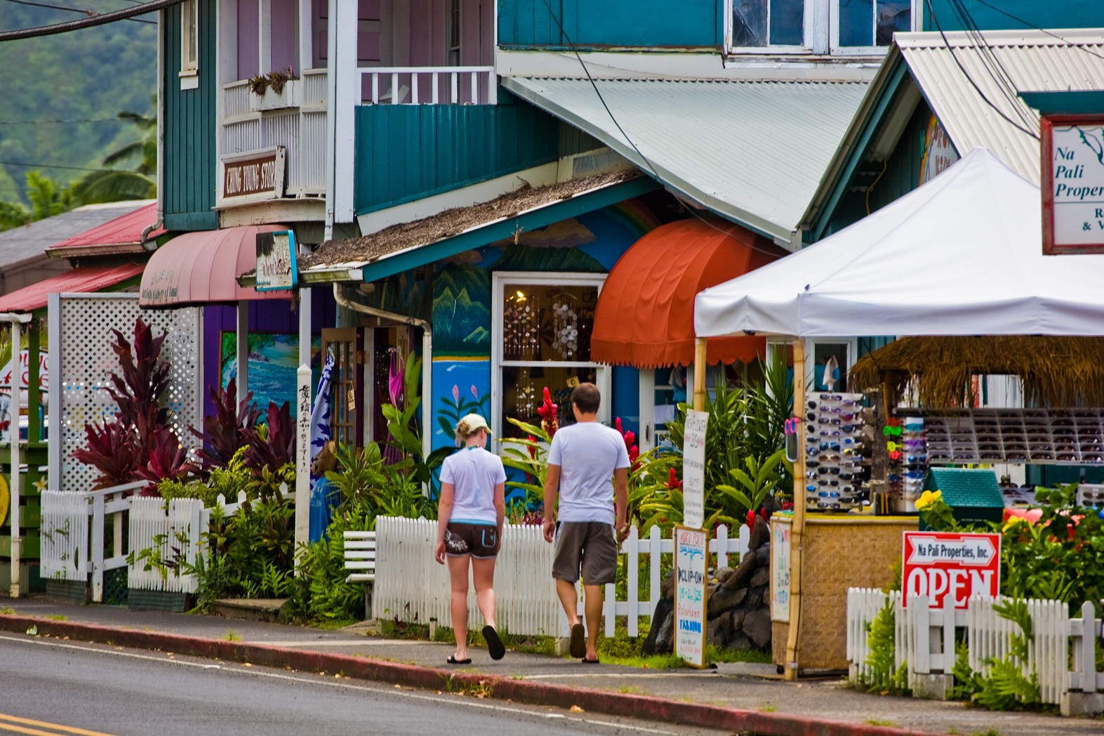 Couple walking past colorful shopfronts and the Ching Young Store in Hanalei town