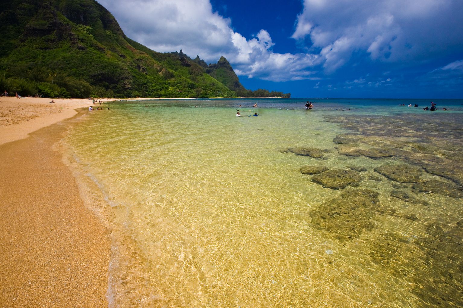 Clear shallow water over the reef at Kēʻē and Tunnels, with Makana rising above the shore