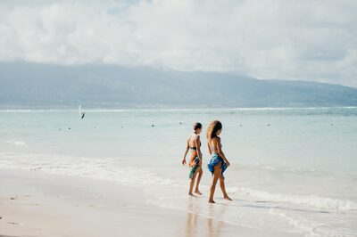 A couple walking along the shoreline at Kanahā Beach Park