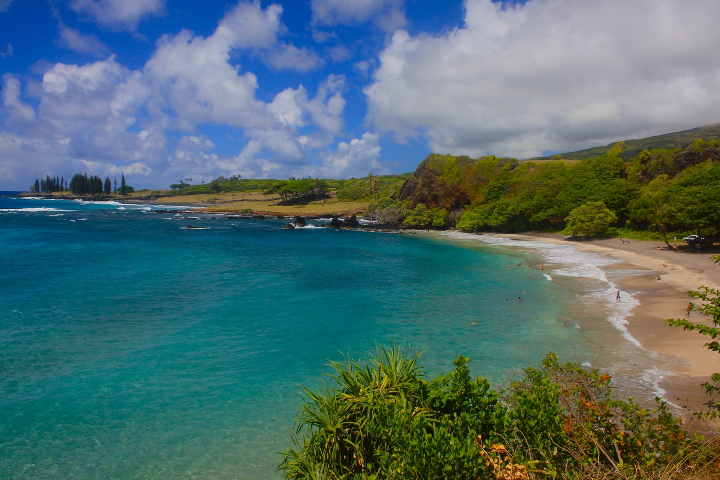 Crescent-shaped Hamoa Beach, with turquoise water, a sandy shore and green hills