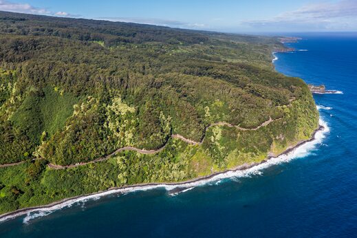Aerial view of the green East Maui coastline and the Road to Hāna winding above the sea