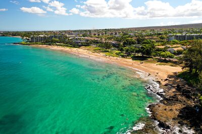 Aerial view of Kamaʻole Beach Park II in Kīhei, golden sand curving along turquoise water