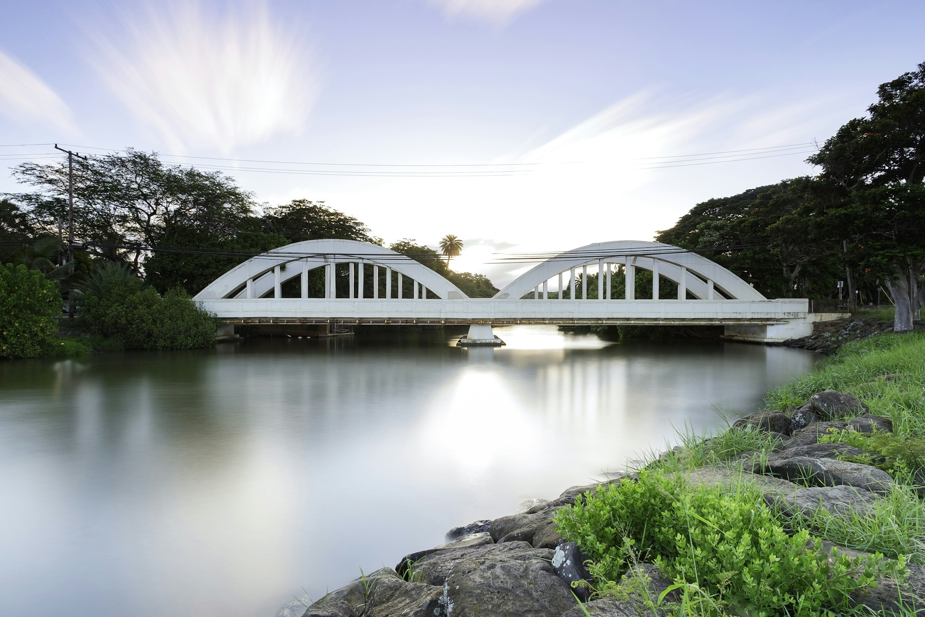 Haleʻiwa’s historic Rainbow Bridge reflected in the calm Anahulu River at sunrise