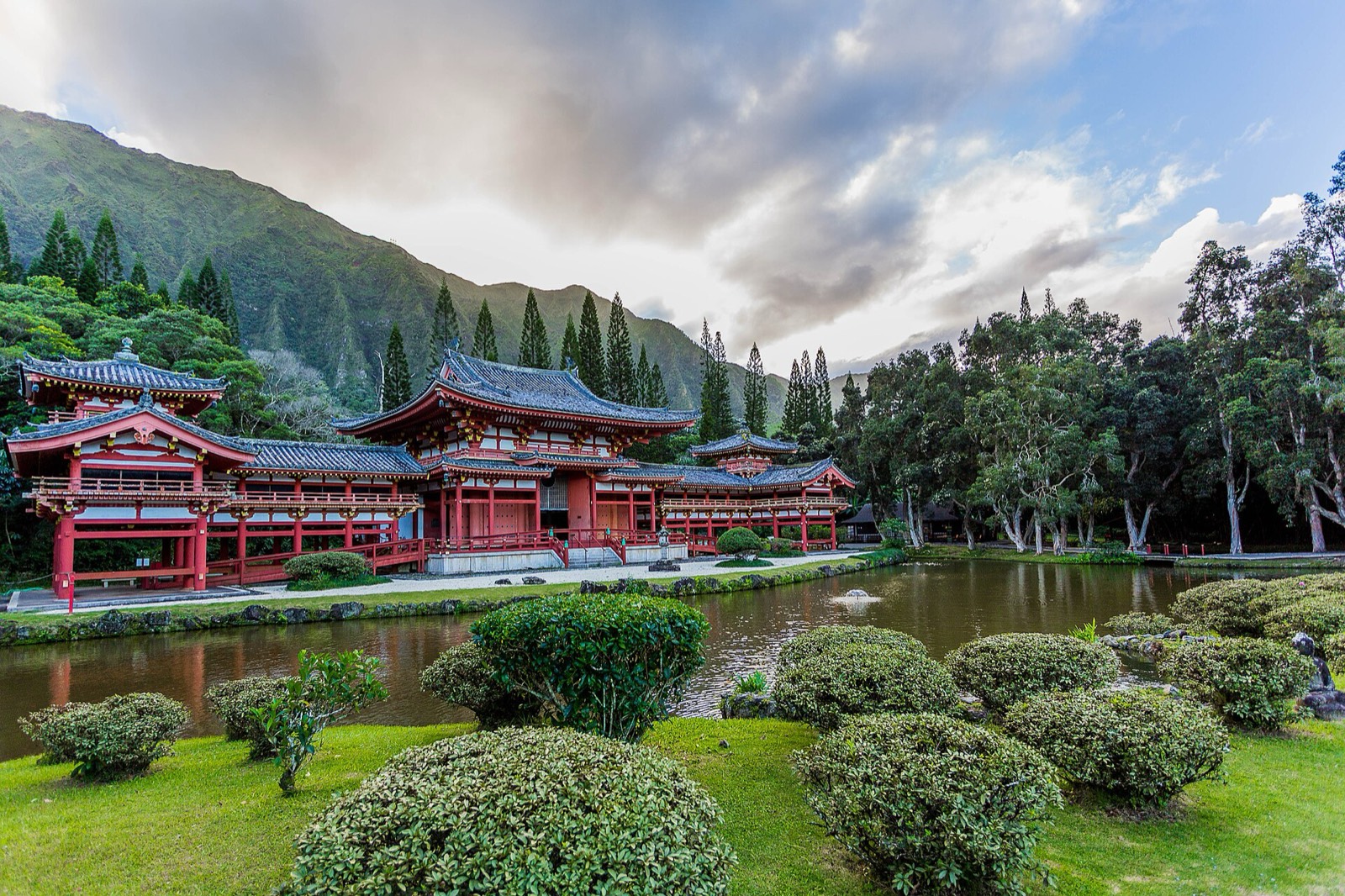 Red Byodo-In Temple beside a reflecting pond and green cliffs